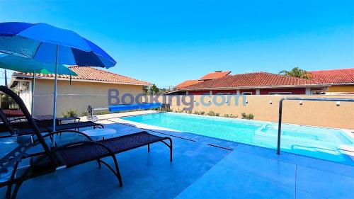 a swimming pool with an umbrella and a table and chairs at Casa Sol da Manhã - Piscina aquecida com hidromassagem - 300m da praia in Guaratuba