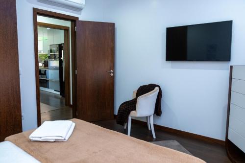 a bedroom with a bed and a chair and a television at Deluxe Villa Home, Peace & Spa in Vila do Conde