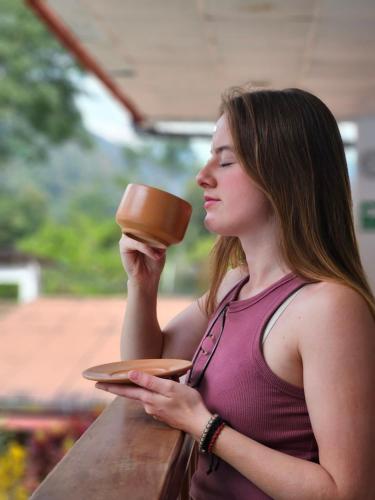 a woman is holding a cup of coffee at Albergue Schuler in San Ramón