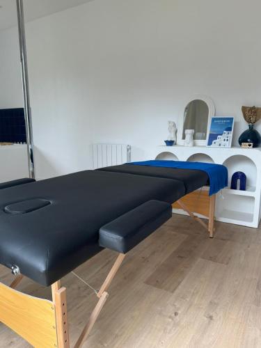 a black bench in a room with a table at Plaisirs Normands in Saint-Julien-de-Mailloc