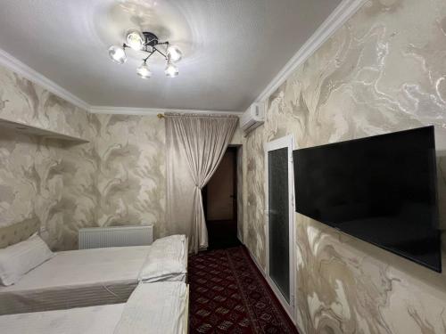 Un dormitorio con una cama y un televisor de pantalla plana. en Islam guest house, en Samarkand
