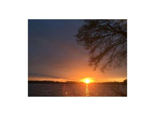 a sunset over the water with the sun in the sky at Bungalow Oberspreewald 5 in Ressen