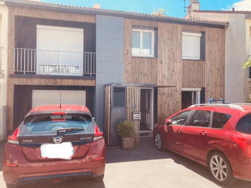 Deux voitures garées sur un parking en face d'une maison dans l'établissement Appartement cosy, à Saint-Sébastien-sur-Loire