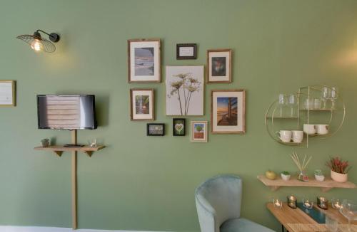 a living room with a tv on a green wall at Entre Terre & Mer SPA in Sainte-Croix-Grand-Tonne