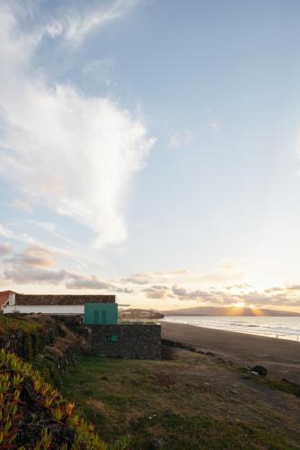 a building on the beach with the ocean in the background at Moinho da Areia - Boutique Hotel in Azores in Ribeira Grande