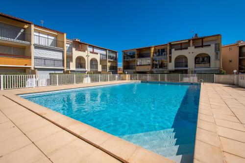 une piscine devant certains immeubles d'habitation dans l'établissement Le Brise Marine - Terrasse - Plage - Piscine - Parking, au Cap d'Agde
