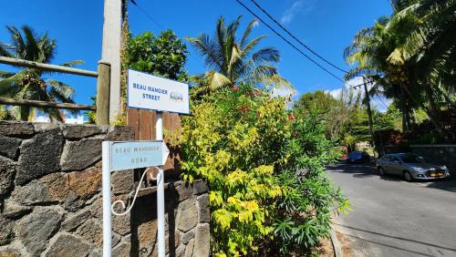 two signs on a stone wall next to a street at 2 bedroom apartment in Bain Boeuf in Cap Malheureux