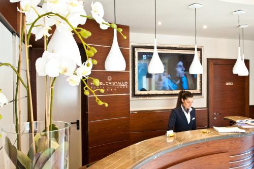 a woman sitting at a desk in a office with flowers at Hotel Garnì Cristallo in Ponte di Legno