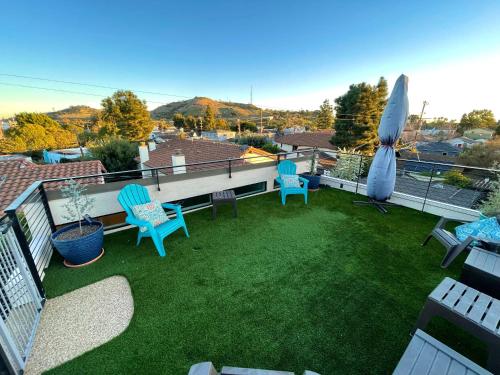 a balcony with a yard with chairs and an umbrella at Cozy Guesthouse with Rooftop Deck in Los Angeles