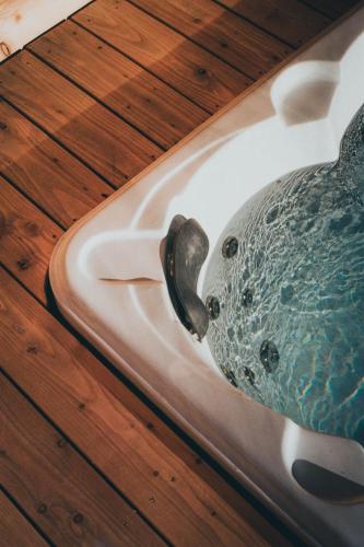 a bath tub with a vase in it on a wooden floor at Chalet Astra, Whirlpool & Sauna in San Pancrazio dʼUltimo