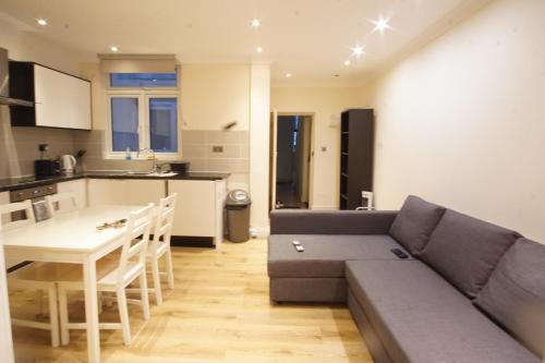 a living room with a couch and a table and a kitchen at Evergreen Apartments- Flat 2 in London