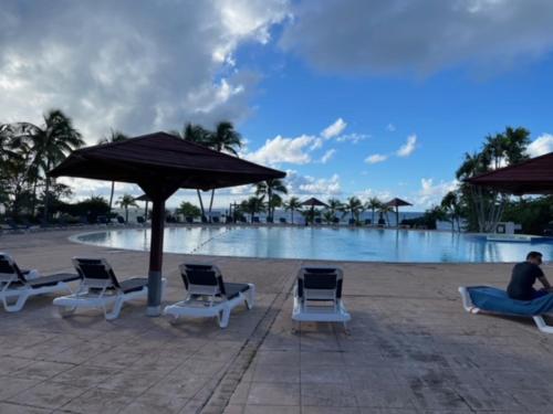 a group of chairs and umbrellas next to a swimming pool at AYOUNAKA, Appartement cosy avec plage terrasse & piscine in Courcelles Sucrerie
