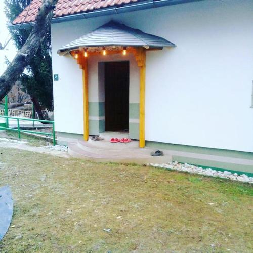 a small white house with a porch with a door at Cottage Eminem with garden and view of Sarajevo in Hadžići