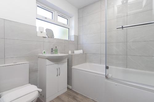 y baño blanco con aseo, bañera y lavamanos. en Large 6BR Home Central Leamington Spa Driveway WiFi, en Leamington Spa