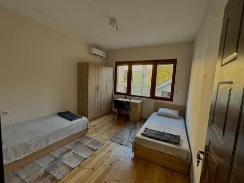 a room with two beds and a desk and a window at Top Spot Pleven in Pleven
