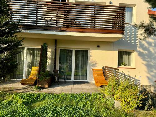 two benches in front of a house with a balcony at Apartamenty Lobeliowy Port in Borzyszkowy