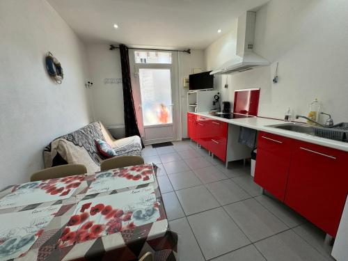 une cuisine avec des placards rouges, une table et un comptoir dans l'établissement Le délice des dunes, à Berck-sur-Mer