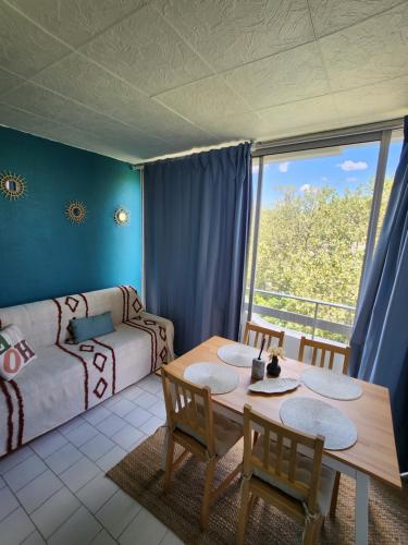 un salon avec une table, des chaises et un canapé dans l'établissement Appart Grande motte Quartier Couchant - Parking - Balcon- Piscine - Plage 300m, à La Grande Motte