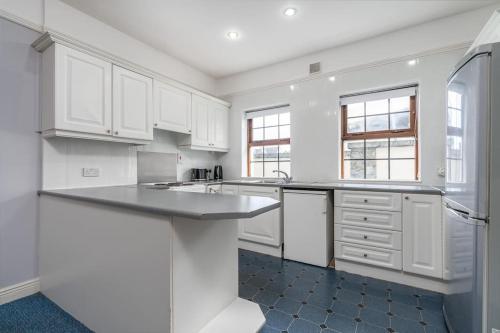 a kitchen with white cabinets and a counter top at City Centre Townhouse - just off Medieval Mile in Kilkenny