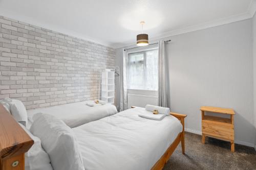 two beds in a room with a brick wall at A Charming 3 Bed home next to NEC and Birmingham International Airport in Marston Green