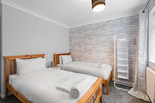 two beds in a room with a brick wall at A Charming 3 Bed home next to NEC and Birmingham International Airport in Marston Green