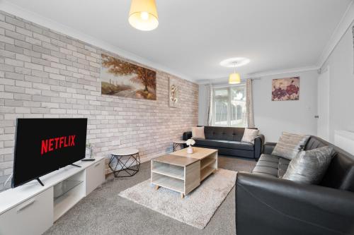 a living room with a tv and a brick wall at A Charming 3 Bed home next to NEC and Birmingham International Airport in Marston Green
