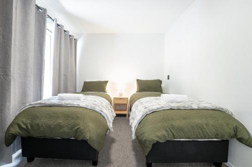 two beds in a room with a table and a window at Lakeview Haven in Queenstown
