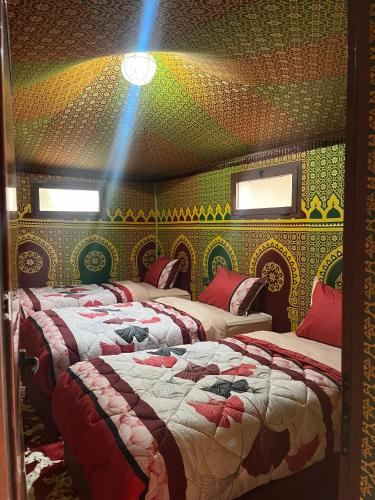 two beds in a room with colorful walls and windows at Villa Maroua in Madkhal Meski