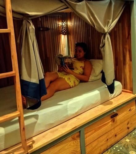 a woman sitting on a bunk bed reading a book at Mediterraneo Youth Hostel in Asuncion