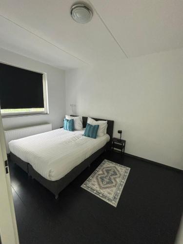 a bedroom with a bed with white sheets and blue pillows at In Almere, Close to Amsterdam in Almere