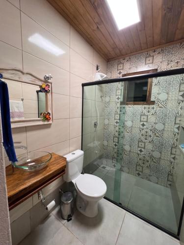 a bathroom with a toilet and a glass shower at Casa Descanso Acuruí in Itabirito