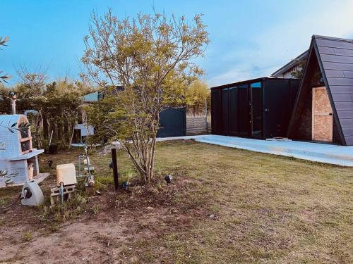 a black house with a tree and a building at 1棟貸し ビーチまで徒歩3分 プライベートバレルサウナ有り 近くにコンビニ スパ有り in Jōnouchi