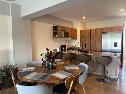 a kitchen with a wooden table and chairs and a kitchen with a counter at Departamento acogedor con vista al mar y alberca in Conchal