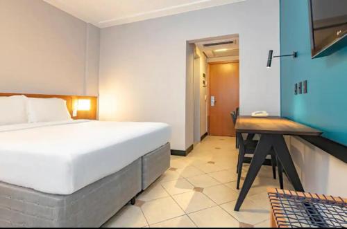 a bedroom with a bed and a wooden table at Suíte Master Particular Alto Padrão com Vaga e Estrutura de Hotel em Florianópolis in Florianópolis