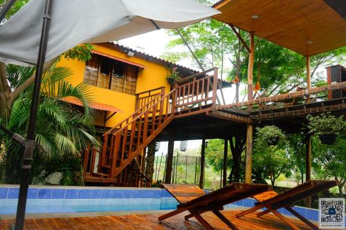 une maison avec un escalier, deux chaises et un parasol dans l'établissement Caminito del Sol Cabaña cerca al mar en Palmarito, à Carretal