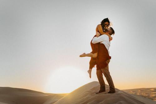 a man carrying a woman in the desert at Sahara Zen Luxury Camp in Merzouga