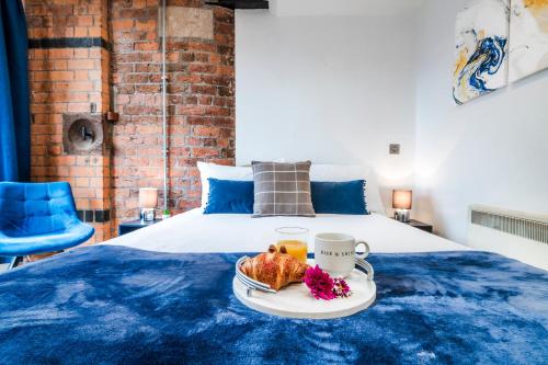 a bed with a blue bedspread with a tray of food on it at Spacious 2-Bed Apartment in Liverpool Cavern Quarter - Minutes from Bars and Live Music by Garudy Serviced Apartments in Liverpool