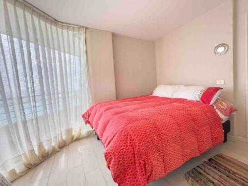 a bedroom with a bed with a red blanket and a window at Departamento Grande en San Alfonso del Mar 4D 3B 2EST in Algarrobo