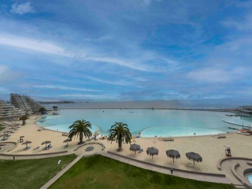 a large pool of water with palm trees and a beach at Departamento Grande en San Alfonso del Mar 4D 3B 2EST in Algarrobo