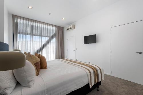una camera da letto con un grande letto bianco con una finestra di Southwark Hotel & Apartments a Christchurch