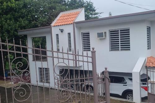 a white house with a gate and a car parked in front at Pal Campo in Hucares