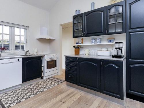 a kitchen with black cabinets and white appliances at 4 person holiday home in Karrebæksminde in Karrebæksminde