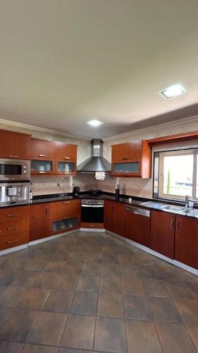 a large kitchen with wooden cabinets and a window at Casa Laurinda- Casa Inteira Marco de Canaveses in Marco de Canaveses