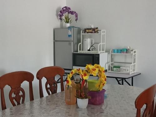 a kitchen with a table with flowers and a refrigerator at HOMESTAY KAPAR KLANG Homestay Balqis in Kapar