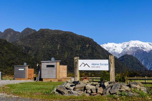 フランツ・ジョセフにあるAlpine Escapeの小さな家の横にある岩山の横にある看板