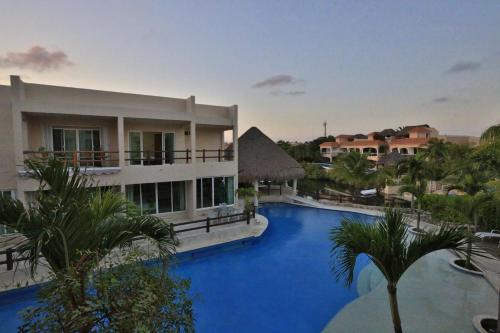 a resort with a large swimming pool next to a building at Coral Maya Stay Suites in Puerto Aventuras