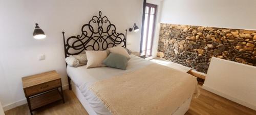 a bedroom with a bed and a stone wall at Casita con jardin en Sada in San Andrés de Carnoedo
