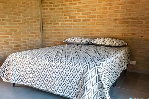 a bed in a room with a brick wall at Cozy corner on Feiticeira Beach in Ilhabela