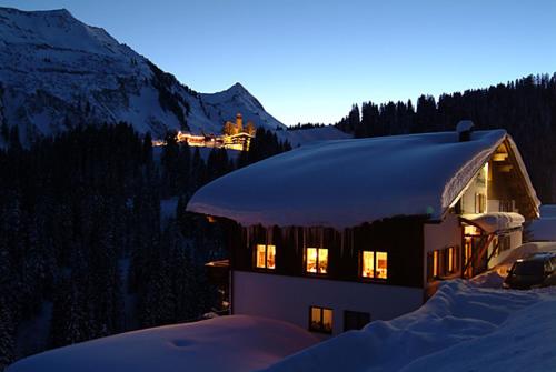 a house in the snow with lights in the windows at Hotel Sonnalpen in Damuls