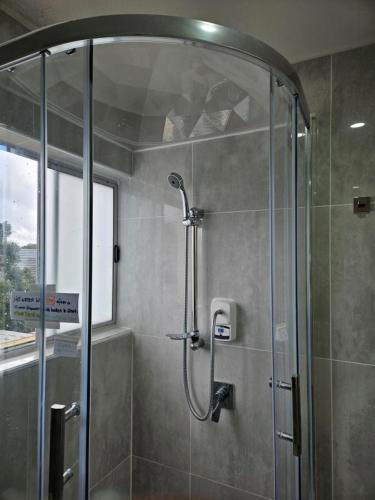 a shower with a glass door in a bathroom at Book Now Affordable Cute Cozy studio with Carpark 23 in Auckland